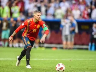 A soccer player is skillfully kicking the ball in front of a captivated crowd, showcasing their talent as one of the 25 best defenders of all time.
