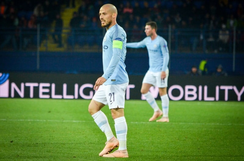 A soccer player from the Premier League is standing on the field.