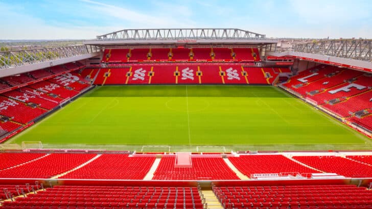 A soccer stadium with red seats and a green field.