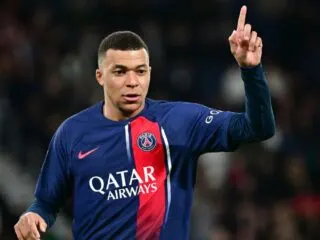 A soccer player from Real Madrid is pointing his finger in the air.