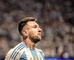 A soccer player in a blue and white striped jersey with the number 10 stands on the field during a game, looking determined as if he's an auto draft pick for success.